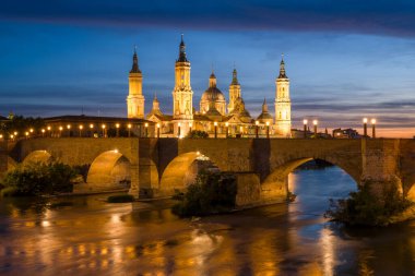 Zaragoza, Espagne - 05: 11: 2024: Güneşli bir günde, Zaragoza, İspanya, Aragon, Zaragoza 'da, geceleyin Sütunun Hanımefendisinin Bazilikası ve Taş Köprüsü. .