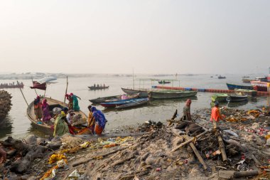 Varanasi, Inde - 03 19 2024: Manikarnika ghat 'taki işçilerin önündeki köpek Asya, Hindistan, Uttar Pradesh, Varanasi, yaz mevsiminde, güneşli bir günde. .