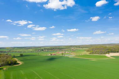 Nievre kırsalındaki canlı yeşil tarlaların ve dağınık çiftlik binalarının hava perspektifi parlak mavi gökyüzünün altında, tüylü bulutlarla çevrili ormanlarla çevriliydi. Manzara gün ışığında ferahlık ve açık alan yayar..