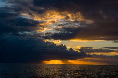 Güneş batarken Adriyatik Denizi 'nin üzerinde yoğun fırtına bulutları toplanıyor ve su üzerinde dramatik bir altın ışığı ve derin gölgeler bırakıyor. Sahnede açık deniz üzerinde çarpıcı bulut oluşumları ve çarpıcı karşıtlıklar yer alıyor..