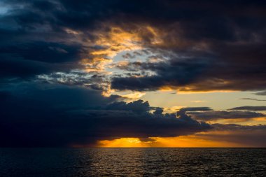Yoğun fırtına bulutlarıyla çarpıcı bir gökyüzü güneş Adriyatik Denizi 'nin üzerinde batarken parlak bir altın parıltısını gözler önüne seriyor. Sahne aydınlık ufuk ve derin gölge arasında çarpıcı bir deniz manzarası oluşturan çarpıcı zıtlıklar içerir..