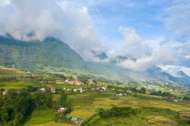 Vietnam yakınlarındaki Sapa 'daki sisli dağların eteklerinde, yeşil ve altın pirinç teraslarının arasında huzurlu bir köy bulunuyor. Yumuşak sabah bulutları, parlak mavi gökyüzünün altında yemyeşil arazide sürükleniyor..