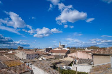 Aigues-Mortes 'in kırsal terasotta çatıları üzerinde geniş bir görüş alanı var. Sembolik Constance Kulesi, canlı mavi gökyüzü, dağınık bulutlar ve canlı bahar ışığı altında..