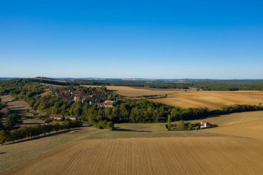 Hava perspektifi, Fransa 'nın orta kesiminde açık mavi bir gökyüzünün altında ormanlık ve nazik tepelerle çevrili geniş altın tarım arazileriyle çevrili küçük bir köy gösteriyor. Açık alanlar ve uzak ufuk, geniş ve kırsal bir hissi çağrıştırıyor.
