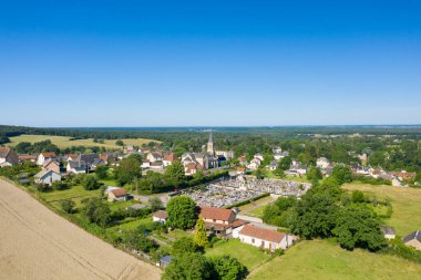 Saint-Honore-les-Bains 'in insansız hava aracı görüntüsü. Huzurlu bir köy, merkezi bir kilise ve tarlalarla, yeşilliklerle ve açık mavi gökyüzüyle çevrili bir mezarlık..