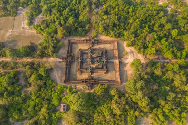 Drone perspektifi, Banteay Samre Tapınağı 'nın Angkor bölgesindeki yoğun orman ve kırsal açıklıklarla çevrili olduğunu gösteriyor. Kadim kumtaşı yapısı, ılık gün ışığında yemyeşil alana karşı duruyor..
