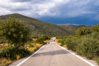 Sessiz bir köy yolu, bereketli tepeler ve vahşi bitki örtüsünün arasından geçiyor, dramatik, karanlık bulutların altından geçen keçilerle birlikte. Manzara doğal dokular, açık alan ve karamsar bir atmosfere sahiptir..
