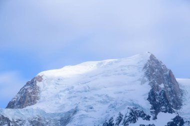 Mont Blanc du Tacul 'un üst yamaçları, Fransız Alpleri' nde yumuşak ve dağınık bir gökyüzünün altında ortaya çıkan engebeli kaya yüzeyleriyle taze kar ve buzla kaplıdır..