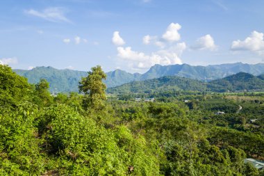 Bereketli yeşil tepeler ve sık orman geniş bir vadi boyunca uzanır. Kuzey Vietnam 'da beyaz bulutlarla kaplı parlak bir gökyüzünün altındaki uzak dağ sırtları. Manzara canlı gün ışığında tazelik ve doğal güzellik yayar..