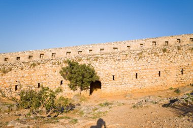 Yunanistan 'ın Nafplio kentindeki Palamidi Kalesi' nin tarihi taş duvarı sıcak öğleden sonra ışığıyla aydınlandı. Engebeli duvarcılık, siperler ve seyrek bitki örtüsü, zamansız Akdeniz gücünü çağrıştırıyor..