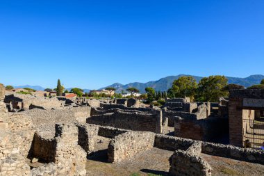 Antik taş duvarlar ve Roma binalarının kalıntıları Pompeii, İtalya 'nın arkeolojik bölgesi boyunca uzanır, yemyeşil ağaçlar ve parlak mavi gökyüzünün altında yükselen Apennine dağları. Günışığı kalıntıları ve açık arazi,