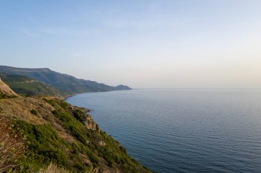 Sardunya 'nın Alghero ve Bosa arasında sakin bir kıyı şeridi. Yeşil yamaçlar yumuşak, berrak akşam ışığı altında sakin mavi Akdeniz' le buluşuyor..