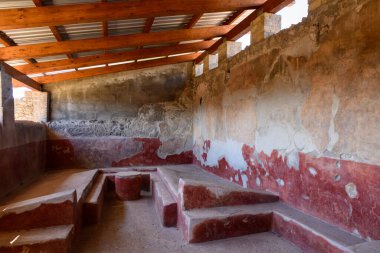 İtalya 'nın Pompeii kentindeki Achilles Evi' nin korunmuş bir Roma yemek odasında solmuş kırmızı alçı ve ahşap bir çatı altında yıpranmış duvarlar bulunuyor. Kırsal dokular ve geometrik oturma tarihi