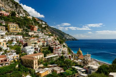 Canlı pastel binalar ve sembolik sarı kubbeli kilise, Amalfi Sahili 'nin berrak mavi sularına bakan Positano, İtalya' nın dik yamacından aşağı taşar. Yeşillik ve engebeli kayalıklar bu güzel Akdeniz köyünü çerçeveliyor.
