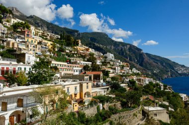 Canlı pastel tonlarda teraslı evler, Amalfi Sahili 'nin derin mavi sularına tepeden bakan Positano, İtalya' nın dik yamaçlarında çağlarlar. Manzara yemyeşil, engebeli kireçtaşı dağlarını ve parlak Akdeniz gökyüzünü yakalıyor.