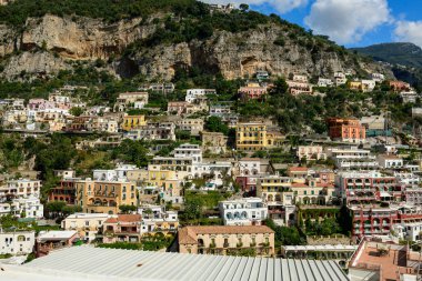 Pastel tonlarda renkli binalar, parlak bir gökyüzü altında, engebeli kireçtaşı uçurumlarına ve yemyeşil yeşilliklere karşı İtalya 'nın Positano kentinin dik yamaçlarında dalgalanır. Canlı mimari ve katmanlı teraslar çarpıcı bir Akdeniz yaratıyor.