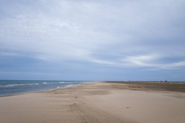 Port Saint Louis du Rhone 'daki Plage Napolyon' da sonsuz kum tabakası hafif dalgalarla karşılaşır. Tepemizde, dağınık bulutlardan oluşan bir örtü sakin ve ferah bir sahil havası yaratır..