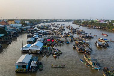 Geniş bir hava perspektifi, Can Tho, Mekong Delta, Vietnam 'daki Cai Rang yüzer pazarının enerjik görüntülerini yakalar. Nehir boyunca taze meyve kümeleriyle yüklü sayısız tekne nehir kenarındaki evlerle çevrili ve yumuşak yeşillikler altında.