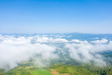 Beyaz bulutlar yemyeşil bir vadi ve Dien Bien Phu, Vietnam 'daki uzak dağların üzerinde sürükleniyor. Parlak mavi gökyüzü ve yumuşak güneş ışığı sakin ve geniş bir atmosfer yaratır..