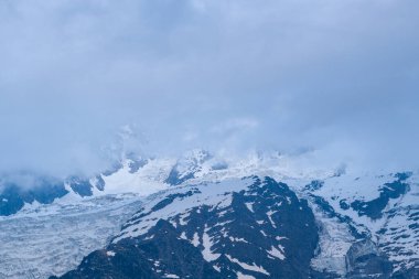 Tırtıklı dağ yamaçları ve buzlu buzullar, Fransız Alpleri 'nde karamsar ve gizemli bir dağ manzarası yaratan alçak asılı bulutlar tarafından kısmen gizleniyor..