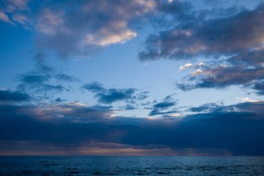 Katmanlı bulutlarla dolu mavi bir gökyüzünün altındaki Adriyatik Denizi 'nin geniş manzarası. İnce renk ve yumuşak ışık grafikleri sakin ve açık bir deniz manzarası yaratır..