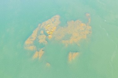 Stoeng Treng yakınlarındaki Mekong Nehri 'nin berrak turkuaz suyunun altında günışığı kayaları ve küçük çalılar belirir. Yumuşak dalgalar ve batık dokular yukardan çok az bir kompozisyon oluşturur..