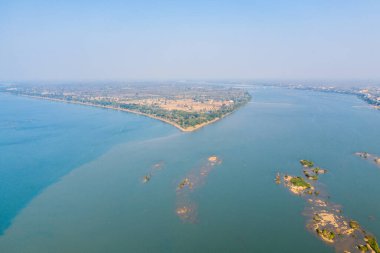 Mekong Nehri 'nin Stoeng Treng, Kamboçya' daki araziyle buluşmasına geniş bir hava perspektifi. Geniş mavi sular, kumlu kıyılar ve dağınık adalar berrak gökyüzünün altında sakin bir nehir manzarası oluşturur..