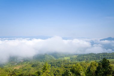 Beyaz bulutlar, Dien Bien, Vietnam 'da açık mavi gökyüzünün altında yuvarlanan orman tepeleri olan yemyeşil bir vadinin üzerinde süzülüyor. Parlak gün ışığı taze, havadar bir dağ atmosferi yaratır..