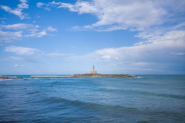 İtalya 'nın Vieste kıyısındaki Santa Eufemia adasında, bulutlu bir gökyüzünün altında açık mavi Adriyatik sularıyla çevrili bir deniz feneri bulunur. Sakin deniz manzarası, engebeli ada ile geniş ada arasındaki zıtlığı vurguluyor.