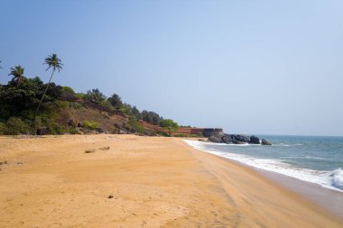 Geniş kumlu kıyı şeridi, bereketli yeşillikler ve açık mavi gökyüzünün altında eğilmiş palmiye ağaçları tarafından çerçevelenmiş tarihi Bekal Kalesi 'ne doğru uzanır. Yumuşak dalgalar kıyıya vurur, sakin bir tropikal manzara yaratır..