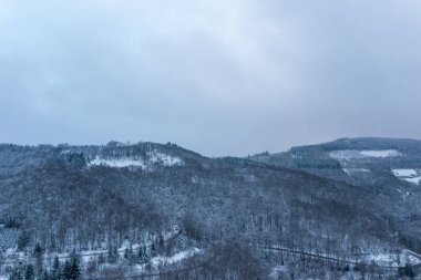 Morvan 'daki yoğun ormanlık tepeler dramatik bulutlu bir gökyüzünün altında taze karla kaplı. İnce mavi tonlar ve yumuşak ışık soğuk ve sakin bir kış manzarasını çağrıştırıyor..