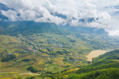 Teraslı pirinç tarlaları, dağınık köyler ve Sapa, Vietnam 'da sürüklenen bulutların altında sakin bir dağ gölü. Bereketli yeşil tepeler ve katmanlı dokular huzurlu bir kırsal alan yaratır..