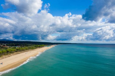 Sardinya 'daki Spiaggia Marina di Orosei üzerinde yemyeşil ve dramatik bulutlarla çevrili turkuaz suların yanında geniş bir kumlu kıyı şeridi uzanır..