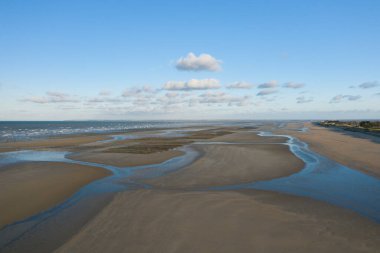 Utah Sahili 'nin alçak gelgitte hava manzarası dalgalı gelgit kanalları ve ıslak kumlar dağınık bulutlarla kaplı parlak mavi bir gökyüzünü yansıtıyor. Açık arazi, bir sükunet ve uçsuz bucaksızlık hissi verir..