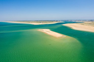 Brittany 'deki Barre dEtel' de canlı yeşil gelgit suyuyla çevrili küçük kumlu bir ada. Geniş hava manzarası açık kıyı şeridini, açık gökyüzünü ve aydınlık bir yaz gününde kara ve denizin buluşmasını yakalar..
