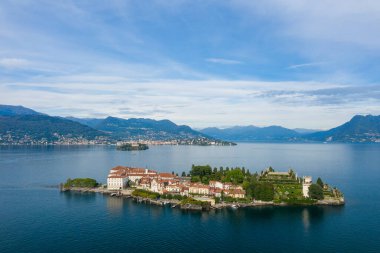 Büyük sarayı ve Maggiore Gölü 'nün derin mavi sularıyla çevrili süslü bahçeleriyle Isola Bella' nın hava perspektifi. Alp dağları ve göl kentleri, yumuşak bulutlarla kaplı bir gökyüzünün altında manzaralı bir zemin oluşturur.