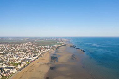 Lion-sur-Mer 'in yüksek irtifa görüntüsü, temiz bir gökyüzünün altında uzanan köyün sakin mavi denizle buluşmasını gözler önüne seriyor..