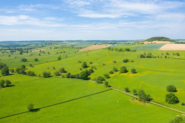 Nivernais kırsalında, açık mavi gökyüzü altında ağaçlarla kaplı yeşil çayırlar ve çitlerle bölünmüş tarım arazilerinin geniş hava manzarası..