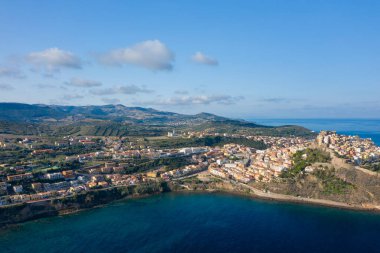 Castelsardos 'un geniş hava manzarası engebeli kıyı şeridi boyunca renkli binaları olan, yuvarlanan yeşil tepeler ve parlak bir gökyüzünün altındaki açık mavi Akdeniz sularıyla desteklenen yeni bir kasaba..