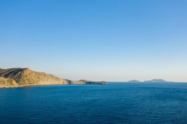 Engebeli kıyı tepeleri ve Girit 'in güney kıyısındaki berrak bir gökyüzünün altındaki uzak adaların sakin mavi körfezinin geniş bir görüntüsü..
