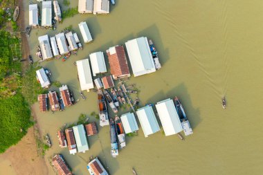 Vietnam 'ın Chau Doc kenti yakınlarındaki nehir kıyısındaki yüzen bir köyün tepeden görünüşü, deniz boyunca demirli ev kümeleri ve ahşap botlarla dolu. Görüntü benzersiz nehir kenarı yerleşimini ve yemyeşil nehir kıyısını yakalıyor. Mekong Deltası 'nın tipik bir örneği..