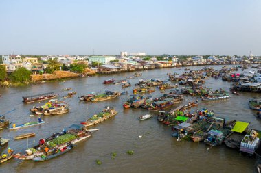 Can Tho, Mekong Delta, Vietnam 'daki Cai Rang yüzer pazarının gündüz görüşü. Nehir kenarındaki evler ve canlı ticari faaliyetlerle çevrili düzinelerce tekne taze ürün ve malla dolu nehirde toplanıyor..