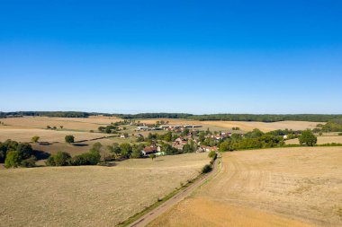 Havadan bakıldığında, Cuncy les Varzy yakınlarında geniş, bulutsuz bir mavi gökyüzünün altında altın tarlalar ve dağınık ağaçlarla çevrili küçük bir köy görülüyor. Açık tarım arazileri ve uzak ormanlık bir dinginlik ve ferah bir hava yaratır.