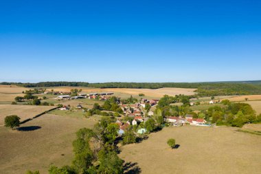 Hava perspektifi açık alanlar, dağınık ağaçlar ve Cuncy les Varzy yakınlarındaki kırsal bölgede canlı, bulutsuz bir mavi gökyüzünün altındaki uzak ormanlık alanlarla çevrili küçük bir kırsal köyü yakalar. Manzara yumuşak yamaçlara, tarım arazilerine sahiptir.