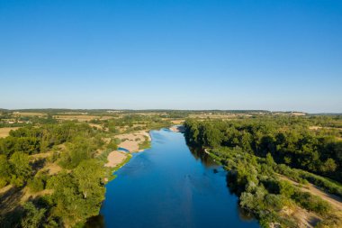 Loire Nehri 'nin yeşil ormanlar ve açık kumlu kıyılar arasında açık mavi gökyüzü altında kıvrılan geniş bir hava perspektifi. Huzurlu manzarada yemyeşil yapraklar, kırsal alanlar ve Nievre bölgesindeki yumuşak su akışı yer almaktadır..