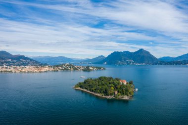 Geniş bir hava perspektifi, Maggiore Gölü 'nün derin mavi sularıyla çevrili Isola Madre' yi uzak kasabalar, ormanlık tepeler ve yumuşak bulutlarla kaplı bir gökyüzünün altında engebeli dağlarla yakalar. Huzurlu kompozisyon adayı vurguluyor