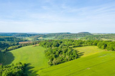 Yeşil tepeler, sık orman arazileri ve Cuncy les Varzy yakınlarında açık mavi bir gökyüzü altında açık tarım arazileri içeren geniş bir hava manzarası baharın canlı ferahlığını yakalıyor..