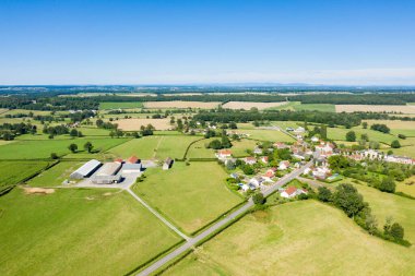 Saint-Germain-Chassenay 'in hava manzarası geniş yeşil tarlalar, tarım arazileri ve parlak mavi gökyüzünün altındaki dağınık ağaçlarla çevrili küçük bir köyü gösteriyor. Sahne açık, güneşli ve huzurlu, temiz kırsal dokular ve uzak ufuklarla.