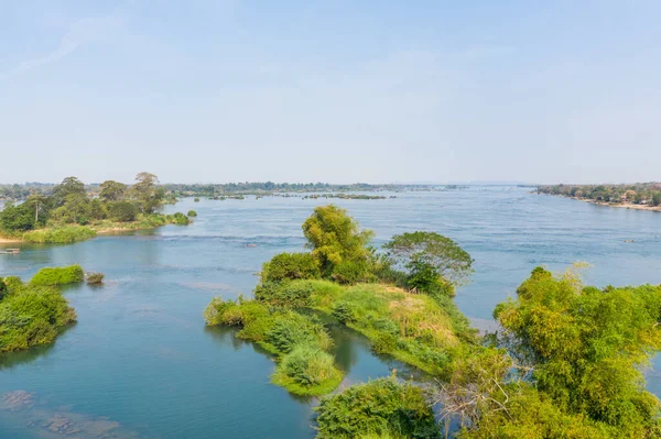 Laos 'un güneyindeki 4000 ada bölgesindeki Mekong Nehri' nin sakin mavi sularından yoğun bitki örtüsüyle kaplı yeşil adacık kümeleri yükselir. Parlak gün ışığı ve geniş açık bir gökyüzü doğal yansımaları olan ferah, sakin bir nehir manzarası yaratır.