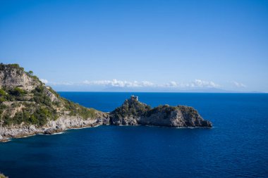 İtalya 'nın Capo di Conca kentindeki engebeli kıyı şeridi derin mavi Akdeniz sularının üzerinde yükseliyor. Issız bir tarihi gözetleme kulesi, yemyeşil yemyeşil ile çevrili kayalık çıkıntıyı taçlandırır ve Amalfi sahili boyunca canlı bir gökyüzüne karşı kurulur..